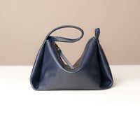 Navy blue handbag on a white surface with a beige background