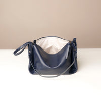 Navy blue handbag on a white surface with a beige background