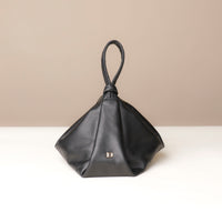 Black handbag with a knot design on a beige background