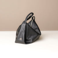 Black leather handbag with a visible brand logo on a beige background