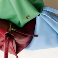 Close-up of a green, brown, and blue leather handbag with a gold clasp.