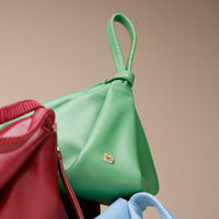 Green handbag with a gold clasp on a beige background