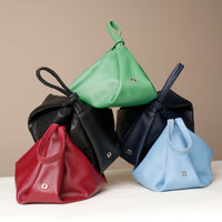 Five leather bags in red, black, green, blue, and black with a beige background