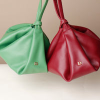 Green and red leather bags with visible brand logo on a neutral background