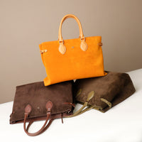 yellow suede leather danilos tote bag and one brown and one green leather bags on a white surface with a beige background
