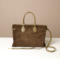 green suede leather danilos  tote bag with a matching strap on a beige background