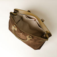 upper view of a opened green suede leather danilos  tote bag with gold accents on a white background
