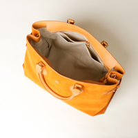 upper view of a opened Yellow suede leather danilos  tote bag with a beige interior on a light background