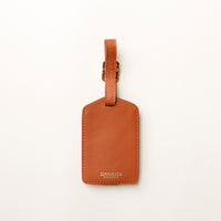 Brown leather luggage tag with 'DANILOS' branding on a white background