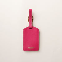 Pink leather luggage tag with 'DANILOS' branding on a light gray background