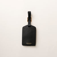 Black leather luggage tag with 'DANILO' branding on a white background