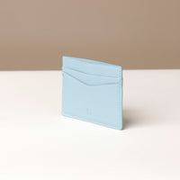 Light blue cardholder on a white surface with a beige background