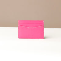 Pink cardholder with visible brand name on a beige background