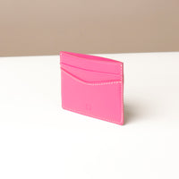 Pink cardholder on a white surface with a beige background