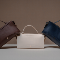 Three Avela Bag with top handle and detachable strap in brown, beige, and blue on a neutral background