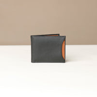 Front of a black pebble leather Milano wallet with a orange card case slot on the side over a beige background