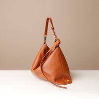 Front view of Zesté Crossbody Lux handbag in panna leather with gold-tone hardware and sculptural silhouette