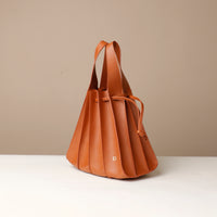 Brown leather handbag on a white surface with a beige background