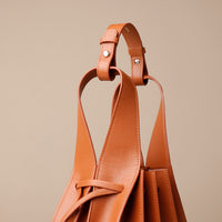 Brown leather handbag with a strap on a beige background