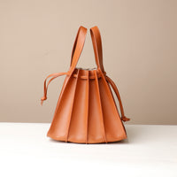 Brown leather bucket bag on a light beige background