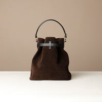 Brown bucket Danilos bag with black handle on a beige background