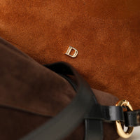 close up of a Brown suede leather bucket bag with a gold Danilos logo on a matching brown background