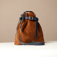 Brown suede handbag with blue strap on a beige background