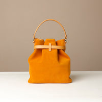 Yellow suede leather bucket Danilos bag with a strap on a beige background