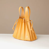 Yellow leather bag with drawstring on a beige background