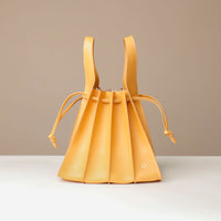 Yellow leather bucket bag on a beige background