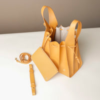 Yellow handbag with matching strap on a white surface