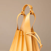 Yellow leather handbag with a strap on a beige background