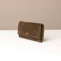 Brown suede Danilos clutch bag on a white surface with a beige background