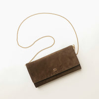 Brown suede Danilos clutch bag with a gold chain on a white background