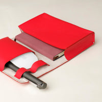 close up view of a open red Danilos Pebble executive accessory holder linea on a beige background