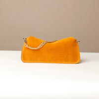 Small Mustard yellow suede leather danilos  handbag with a gold chain on a beige background