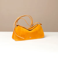 small Yellow suede leather danilos  handbag on a white surface with a beige background