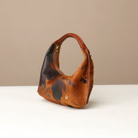Brown leather danilos handbag with black accents on a beige background