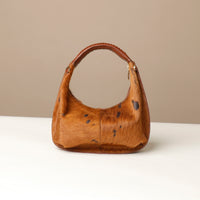 brown cow hair on leather danilos handbag on a beige background
