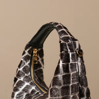 Black hair on textured danilos  handbag with gold zipper on a beige background