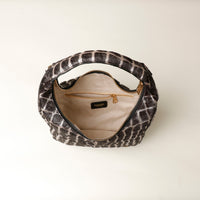 black and grey hair on leather Patterned danilos  handbag with gold zipper on a light beige background