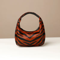 Brown and black zebra-striped hair on leather danilos  handbag on a beige background