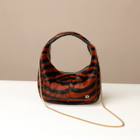 Zebra-patterned hair on leather danilos handbag with gold chain on a beige background