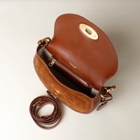 Brown Danilos leather handbag with gold accents on a light beige background