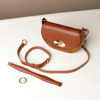 Brown Danilos leather handbag with detachable strap on a white surface
