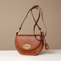 Brown Danilos leather handbag with gold accents on a beige background