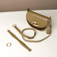 Green Danilos handbag with matching strap and gold ring on a white surface