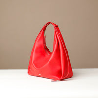 Red handbag on a white surface with a beige background