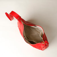 Red leather bag with a gold zipper on a light gray background