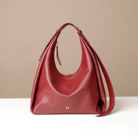 Red handbag with a gold logo on a beige background